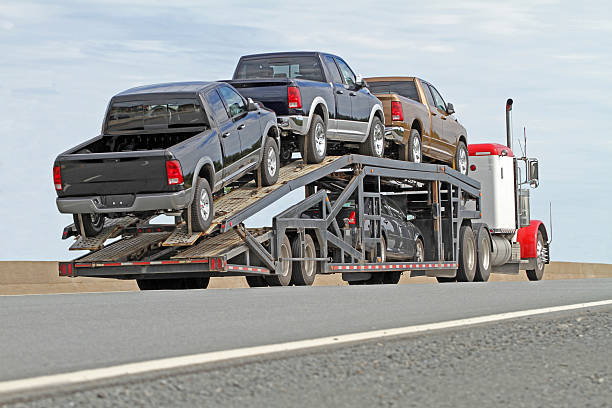 Rear quarter view of a semi truck equipped with a trailer for hauling multiple vehicles.