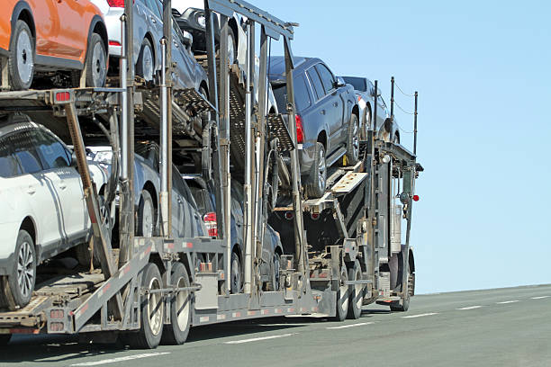 Rear quarter view of a semi truck equipped with a trailer for hauling multiple vehicles.